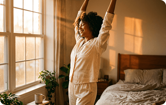 A woman stretching as she wakes in a sunlit bedroom